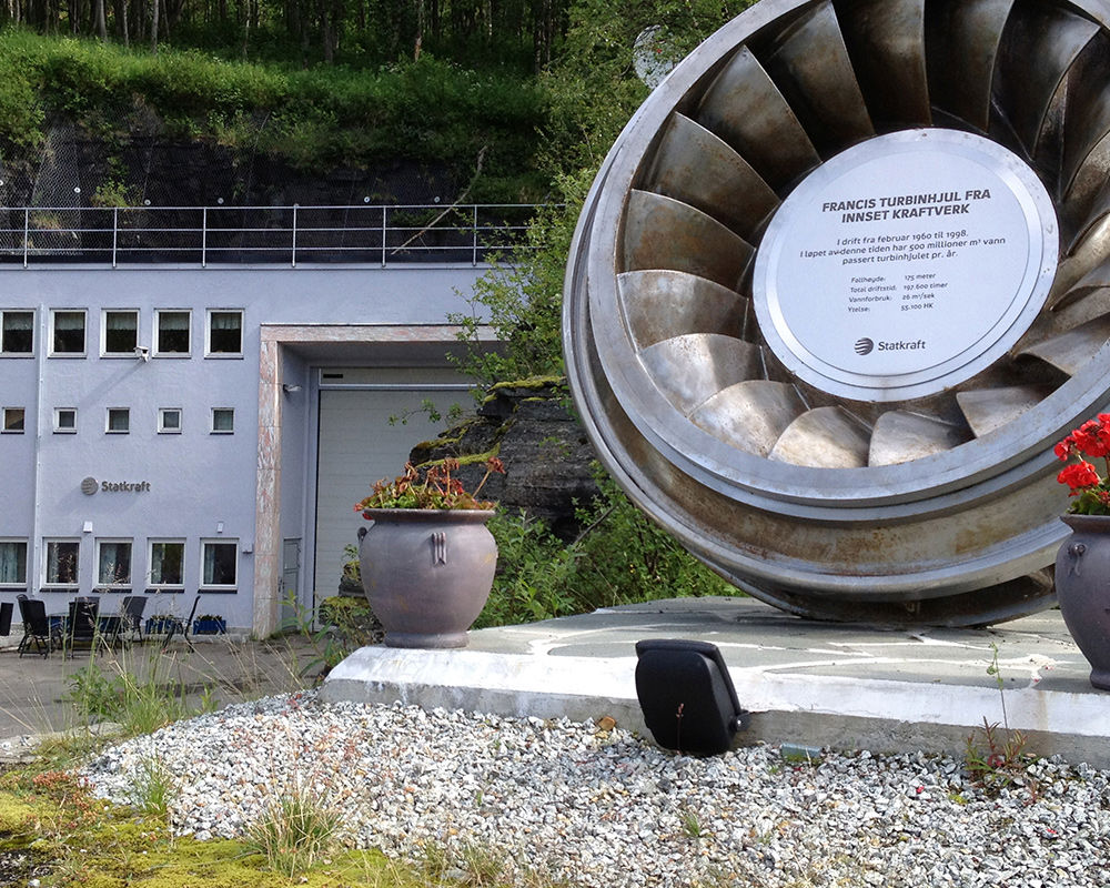Innsett power plant reception building with turbine wheel and anniversary plaque.