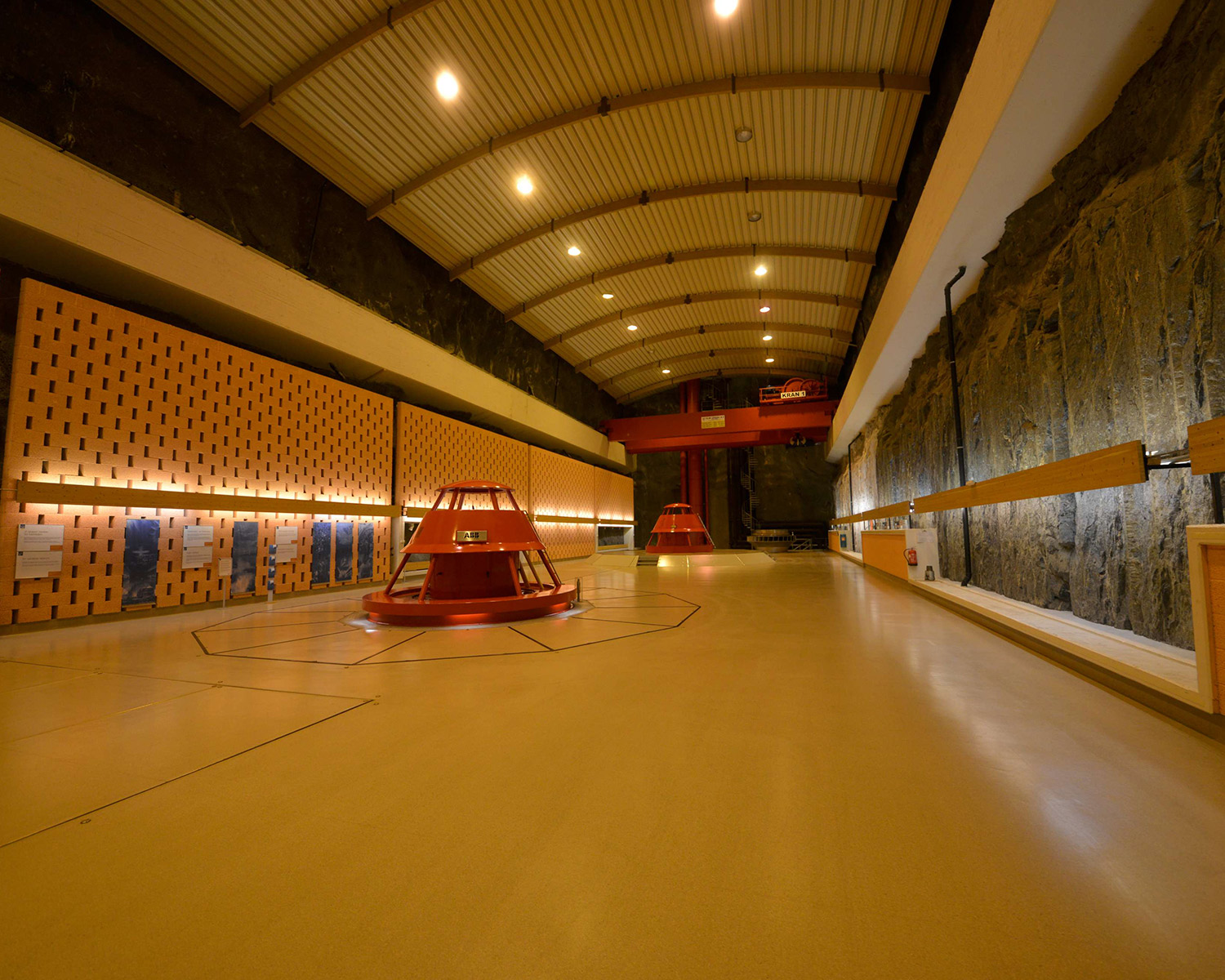 Machine hall with generating units, lighting and bare rock wall.